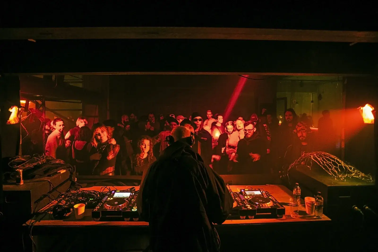 A DJ playing to a crowd in a club lit red