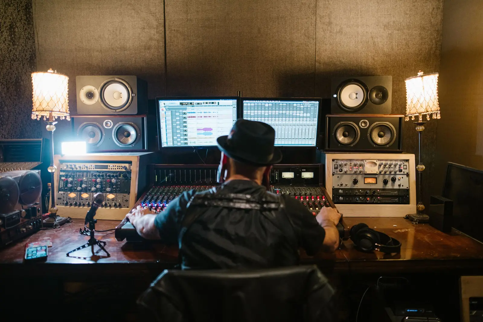 A producer at a mixing desk between studio monitors, seen from behind