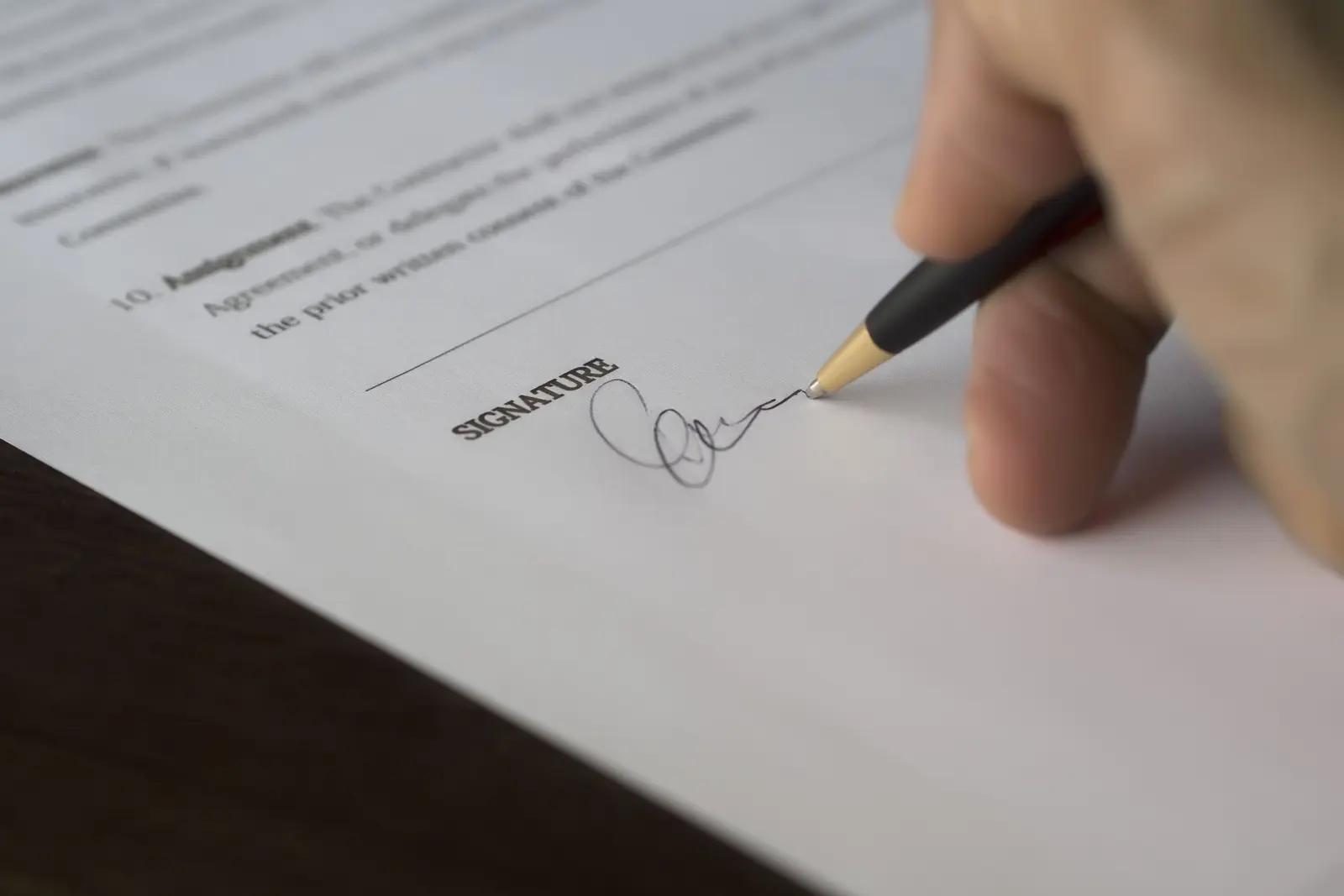 A hand signing a contract with a pen